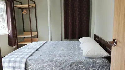 a bedroom with a bed with a blue blanket and white pillows at Baan U-Sabai บ้านอยู่สบาย in Bangkok