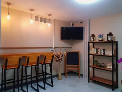 a room with a bar with chairs and a tv at Baan U-Sabai บ้านอยู่สบาย in Bangkok