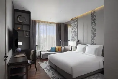 a bedroom with a large white bed and a desk at Sindhorn Kempinski Hotel Bangkok in Bangkok