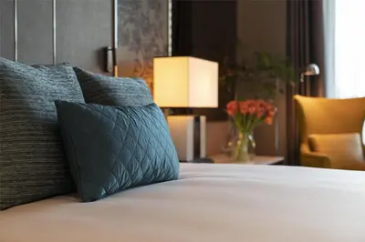 a bedroom with a bed with a pillow and a chair at Sindhorn Kempinski Hotel Bangkok in Bangkok