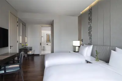 a hotel room with two beds and a desk at Sindhorn Kempinski Hotel Bangkok in Bangkok
