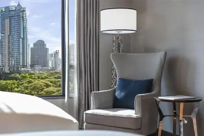 a chair in a hotel room with a window at Sindhorn Kempinski Hotel Bangkok in Bangkok