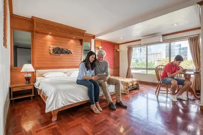 a group of people sitting on a bed in a bedroom at Studio Suite by Royal Ivory Nana in Bangkok