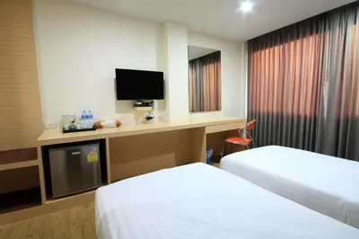 a hotel room with two beds and a desk with a tv at S3 Residence Park in Bangkok