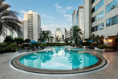 a large swimming pool with palm trees and buildings at Rembrandt Residences Bangkok in Bangkok