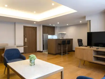 a living room with a tv and a table and chairs at Rembrandt Residences Bangkok in Bangkok