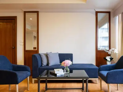 a living room with blue couches and a coffee table at Rembrandt Residences Bangkok in Bangkok