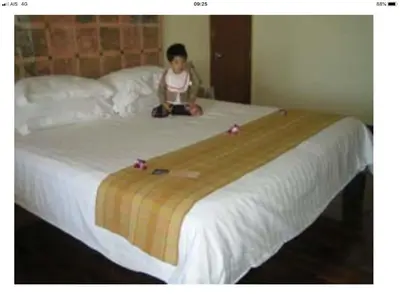 a little girl sitting on top of a bed at BM Mansion in Bangna
