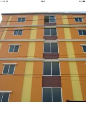 a tall orange and yellow building with windows at BM Mansion in Bangna