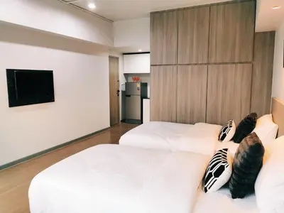 a bedroom with two beds and a tv on a wall at Star Sukhumvit in Bangkok