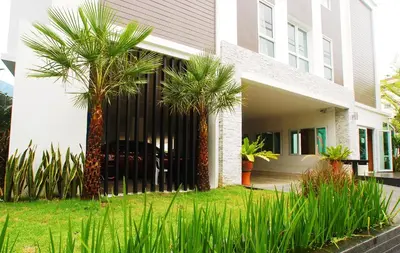 a house with two palm trees in front of it at Riski Residence Ngamwongwan in Nonthaburi