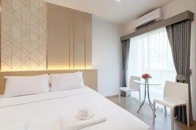 a bedroom with a large white bed and a table at Riski Residence Ngamwongwan in Nonthaburi