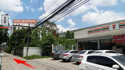 a parking lot with cars parked in front of a pharmacy at Riski Residence Ngamwongwan in Nonthaburi