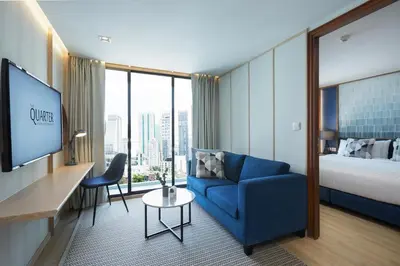 a hotel room with a blue couch and a bed at The Quarter Phromphong by UHG in Bangkok