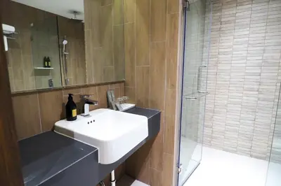 a bathroom with a white sink and a shower at The Quarter Phromphong by UHG in Bangkok