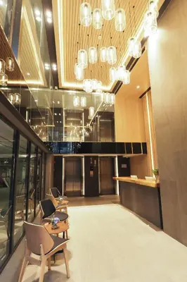 a lobby with chairs and a table and chandeliers at The Quarter Phromphong by UHG in Bangkok