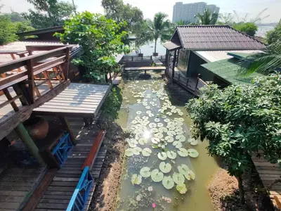a koi pond in a garden next to a house at BAANYA HOMESTAY Ko Kret in Nonthaburi
