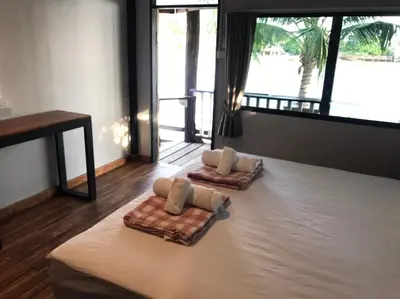 a bedroom with two beds with towels and a table at BAANYA HOMESTAY Ko Kret in Nonthaburi