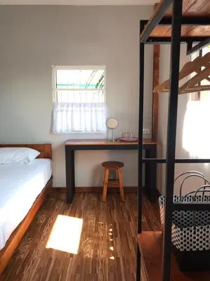 a bedroom with a bed and a desk and a window at BAANYA HOMESTAY Ko Kret in Nonthaburi