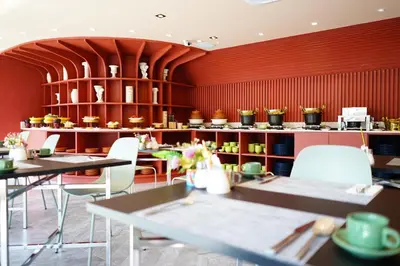 a restaurant with tables and white chairs and red walls at 4 Monkeys Hotel in Bangkok