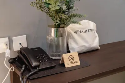 a desk with a phone and a vase with flowers at Woodstory Boutique Hotel in Bangkok