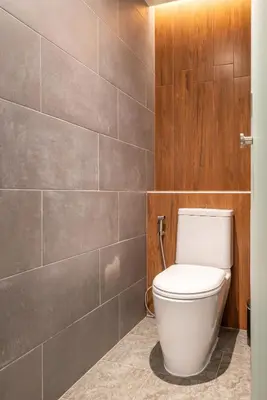 a bathroom with a toilet and a tile wall at Woodstory Boutique Hotel in Bangkok