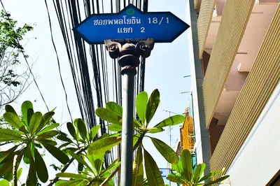a blue street sign on a pole with plants at G9bangkok in Bangkok