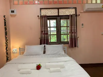 a bedroom with a large white bed with a window at Gaiwandhanat Homestay in Bangkok