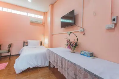 a room with two beds and a tv on the wall at Gaiwandhanat Homestay in Bangkok