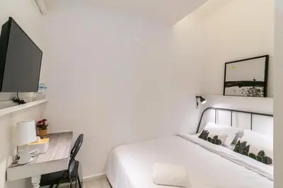 a bedroom with a bed and a desk with a tv at UHU Bangkok in Bangkok