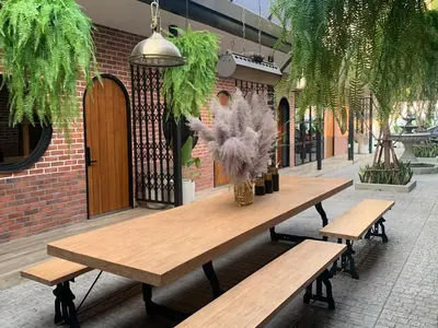 a wooden picnic table with a vase of flowers on it at The Matta in Bangkok