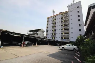 a large white building with cars parked in a parking lot at Sakun Place in Bangna