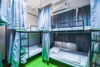 two bunk beds in a room with blue curtains at Ali Hostel in Bangkok