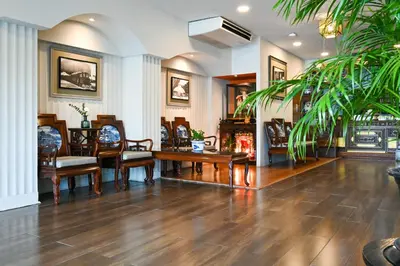 a lobby with chairs and tables and a palm tree at The Krungkasem Srikrung Hotel in Bangkok
