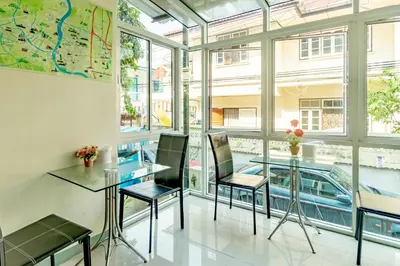 a dining room with a glass table and chairs and windows at Riski Residence Bangkok-noi - Wasit Apartment in Bangkok