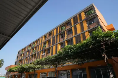 an orange building with plants on the side of it at Fullroom 77 Srinakarin in Samutprakarn