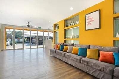 a living room with a couch with colorful pillows at Fullroom 77 Srinakarin in Samutprakarn