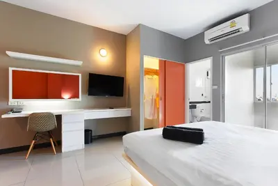 a bedroom with a bed and a desk and a tv at Fullroom 77 Srinakarin in Samutprakarn