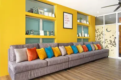 a gray couch with colorful pillows in a room at Fullroom 77 Srinakarin in Samutprakarn