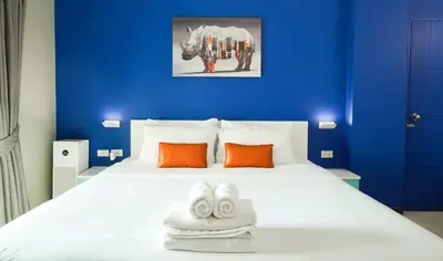a blue bedroom with a bed with two towels at Fullroom 77 Srinakarin in Samutprakarn