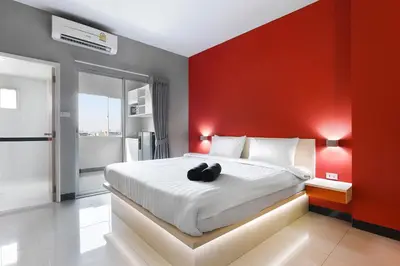 a bedroom with a large bed with a red wall at Fullroom 77 Srinakarin in Samutprakarn