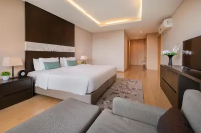 a bedroom with a large white bed and a couch at North Park Serviced Apartment Bangkok in Bangkok