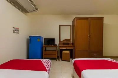 a room with two beds and a desk with a mirror at OYO 583 Sweethome Guest House in Bangkok Noi