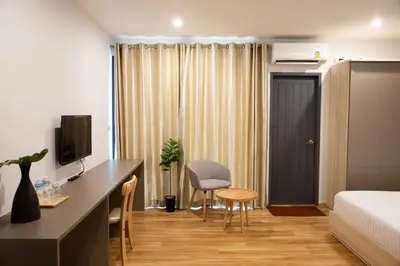 a hotel room with a bed and a desk and a bed and a room with at J & L Residence and Spa in Ban Khlong Khwang Klang