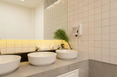 two white sinks in a bathroom with a mirror at Ratchada Hotel - ROTFAI in Bangkok