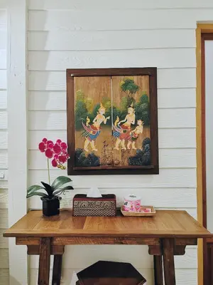 a wooden table with a painting on the wall with a table sidx sidx sidx at TAVEE Guesthouse in Bangkok