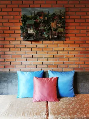 a brick wall with two pillows on a bed at TAVEE Guesthouse in Bangkok