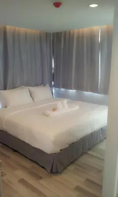 a bedroom with a large white bed with a window at Nantra Ploenchit hotel in Bangkok