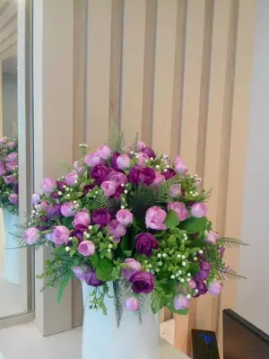 a white vase filled with purple flowers on a table at Nantra Ploenchit hotel in Bangkok