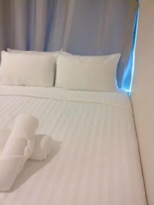 a white bed with a stuffed animal on it at Nantra Ploenchit hotel in Bangkok